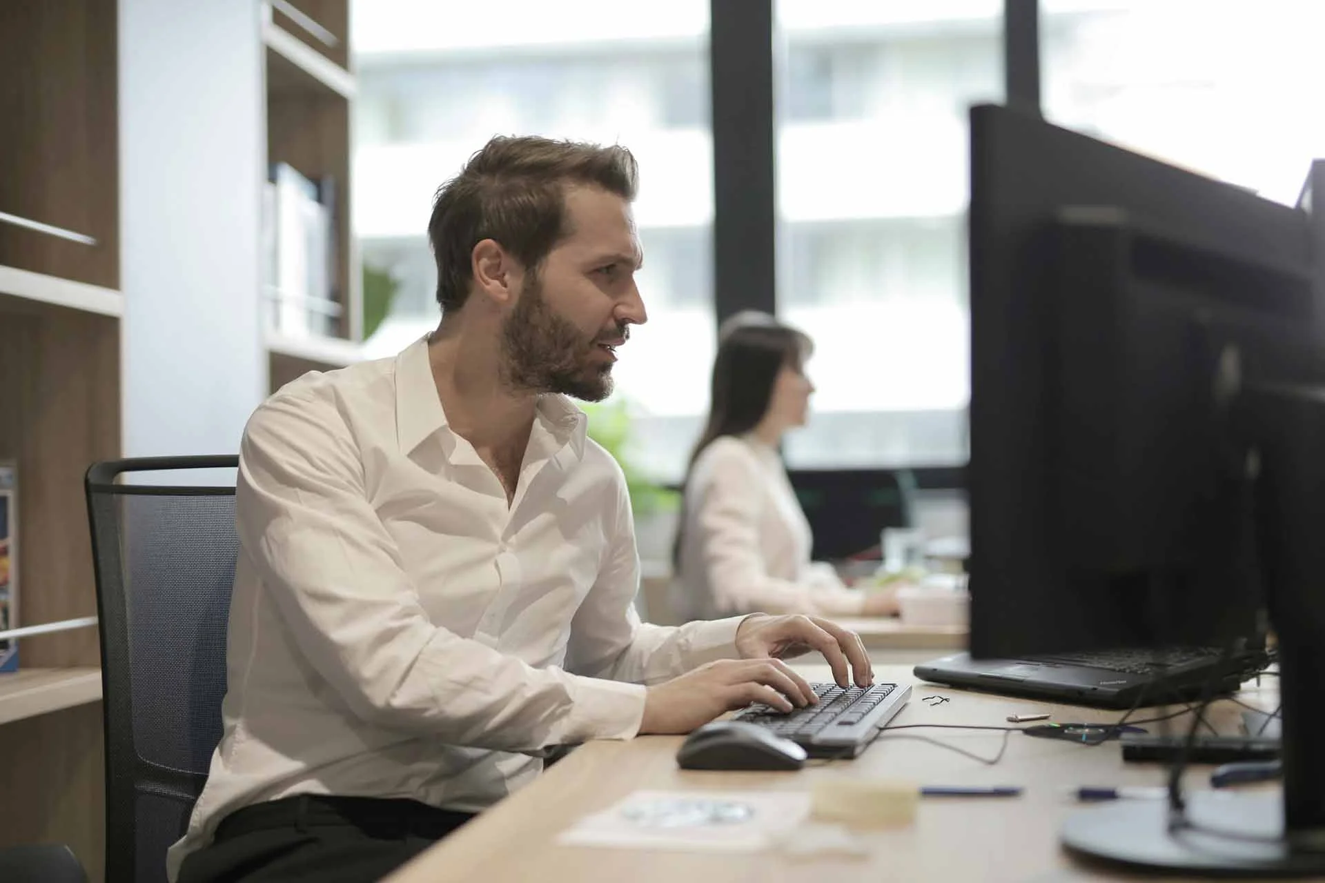 Un cadre assis sur son bureau consultant son ordinateur d'un air très concentré.